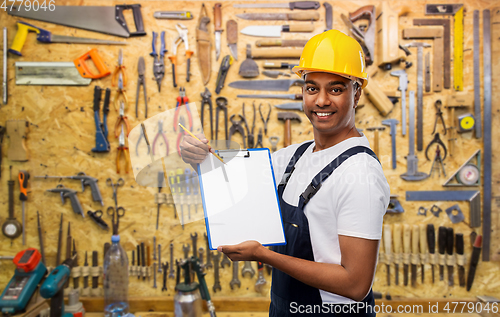 Image of happy builder in helmet with clipboard and pencil