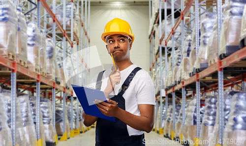 Image of thinking indian worker with clipboard at warehouse