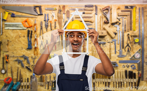 Image of happy indian builder with ruler in shape of home