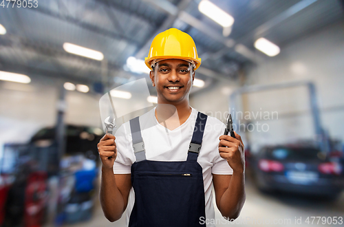 Image of indian mechanic with wrench and pliers at car shop