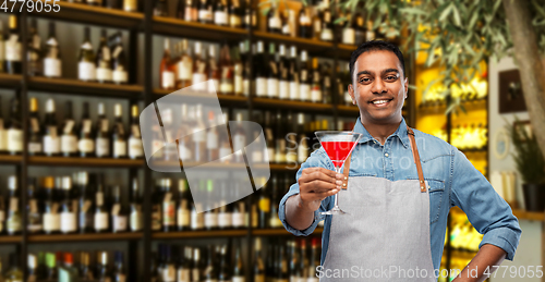 Image of indian barman with glass of cocktail at bar