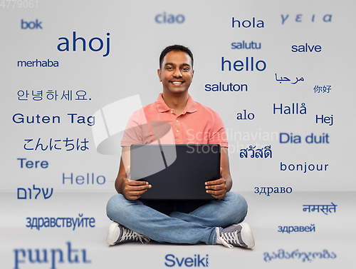 Image of happy indian man with laptop computer on floor