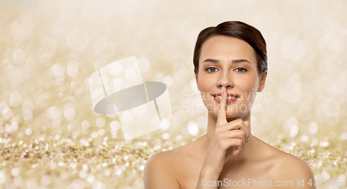 Image of beautiful young woman holding finger on lips