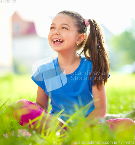Image of Portrait of a little girl sitting on green grass