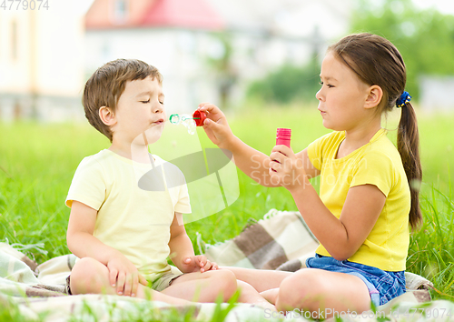Image of Little girl and boy are blowing soap bubbles