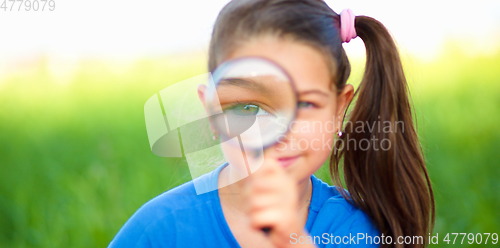 Image of Little girl is looking through magnifier