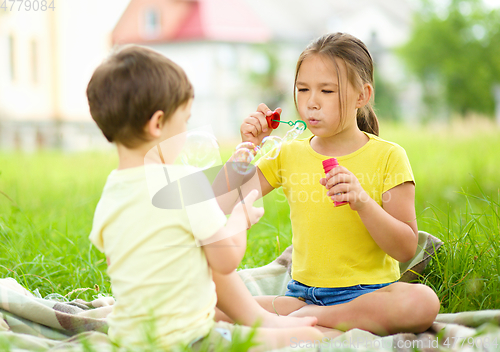 Image of Little girl and boy are blowing soap bubbles