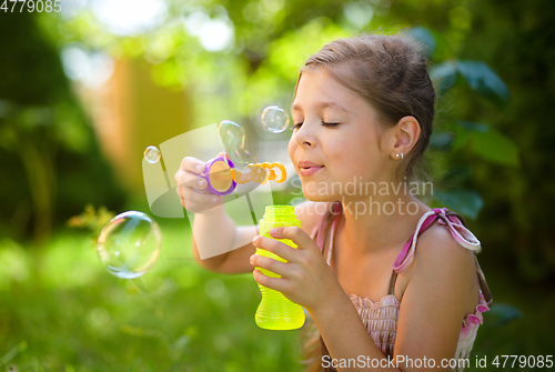 Image of Little girl is blowing a soap bubbles