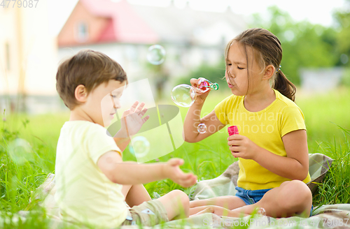 Image of Little girl and boy are blowing soap bubbles