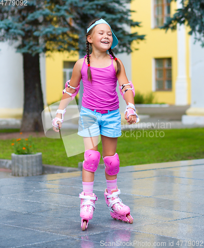 Image of Happy little girl is skating on rollers