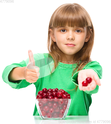 Image of Cute girl is eating cherries showing thumb up sigh