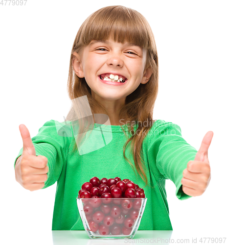 Image of Cute girl is eating cherries showing thumb up sigh