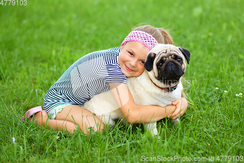 Image of Little girl and her pug dog on green grass