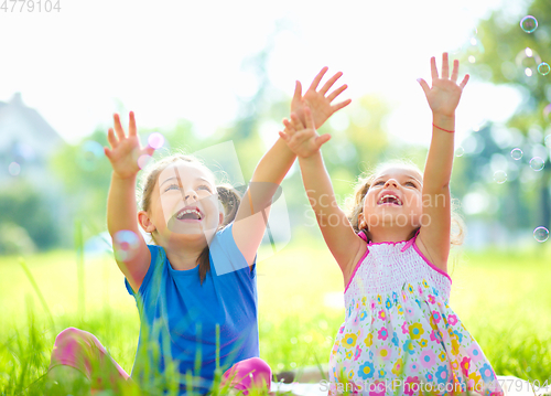 Image of Two little girls are catching soap bubbles