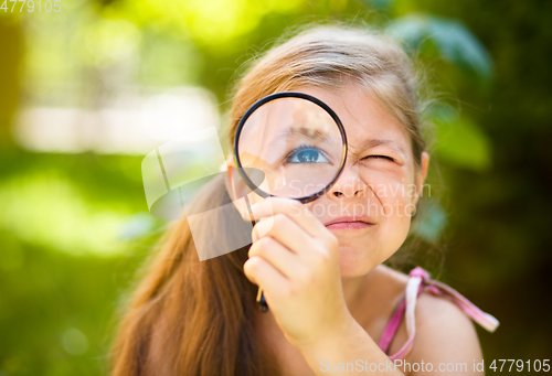 Image of Little girl is looking through magnifier
