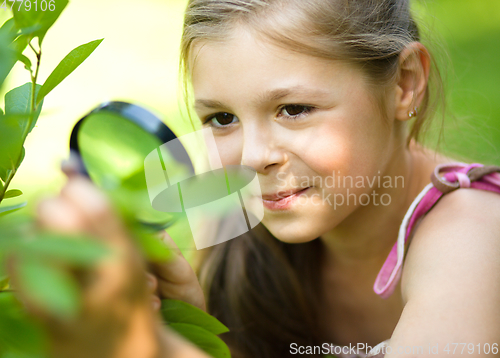 Image of Girl is looking at tree leaves through magnifier