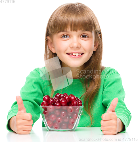 Image of Cute girl is eating cherries showing thumb up sigh