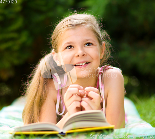 Image of Little girl is reading a book outdoors