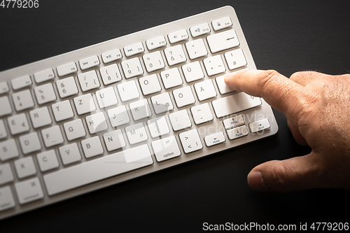 Image of typical computer keyboard with finger on enter