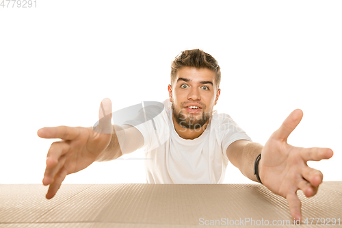 Image of Young man opening the biggest postal package isolated on white