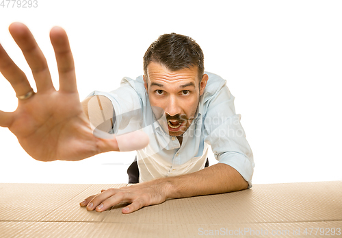 Image of Young man opening the biggest postal package isolated on white