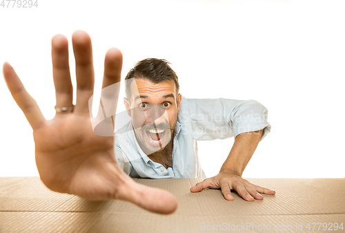 Image of Young man opening the biggest postal package isolated on white