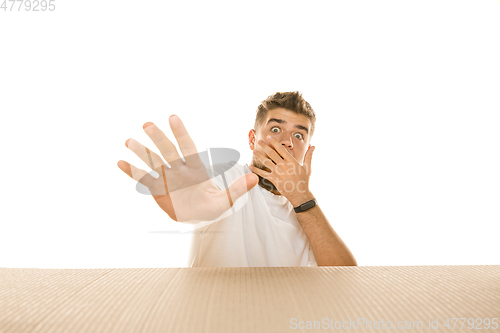 Image of Young man opening the biggest postal package isolated on white