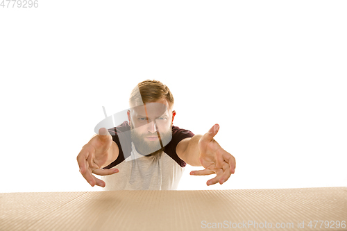 Image of Young man opening the biggest postal package isolated on white