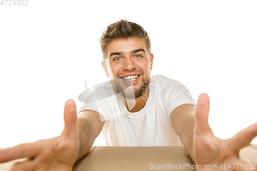 Image of Young man opening the biggest postal package isolated on white