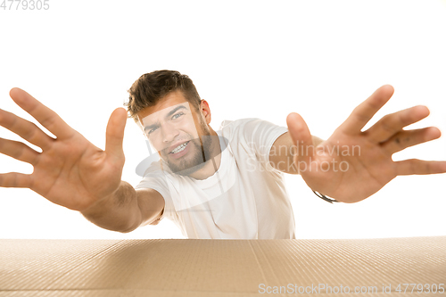 Image of Young man opening the biggest postal package isolated on white