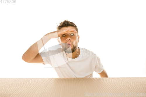 Image of Young man opening the biggest postal package isolated on white