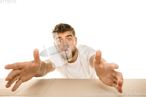 Image of Young man opening the biggest postal package isolated on white