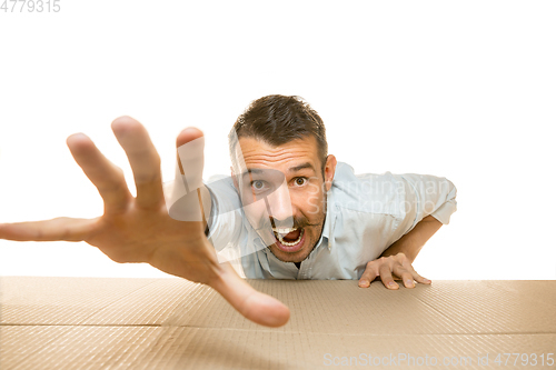 Image of Young man opening the biggest postal package isolated on white