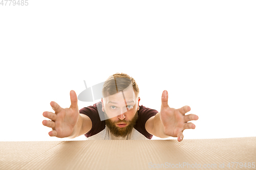 Image of Young man opening the biggest postal package isolated on white