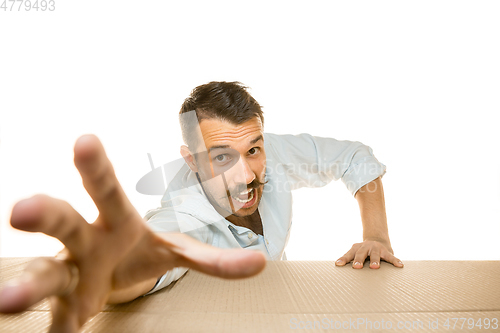 Image of Young man opening the biggest postal package isolated on white