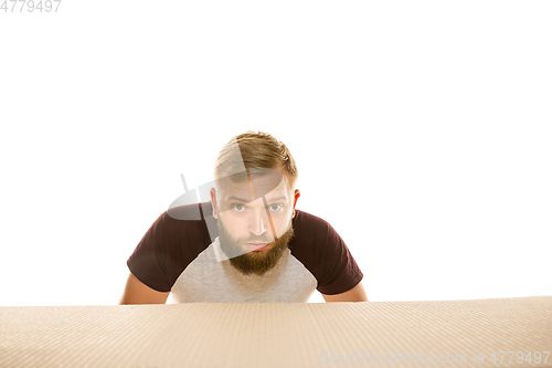 Image of Young man opening the biggest postal package isolated on white