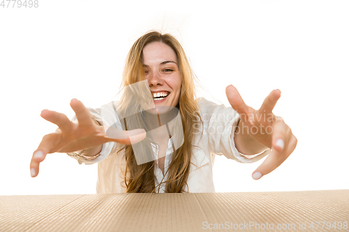 Image of Young woman opening the biggest postal package isolated on white