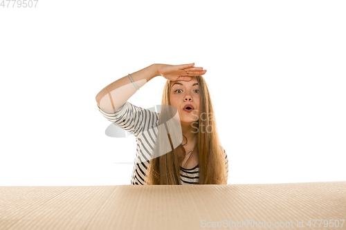 Image of Young woman opening the biggest postal package isolated on white