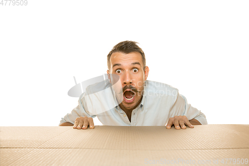 Image of Young man opening the biggest postal package isolated on white