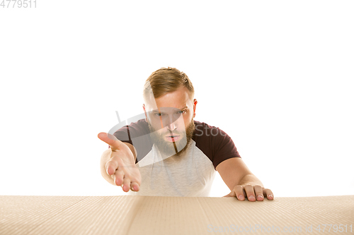 Image of Young man opening the biggest postal package isolated on white