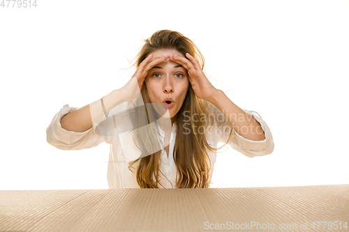 Image of Young woman opening the biggest postal package isolated on white