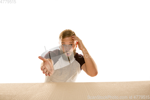 Image of Young man opening the biggest postal package isolated on white