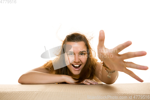 Image of Young woman opening the biggest postal package isolated on white