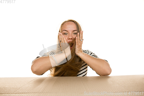 Image of Young woman opening the biggest postal package isolated on white