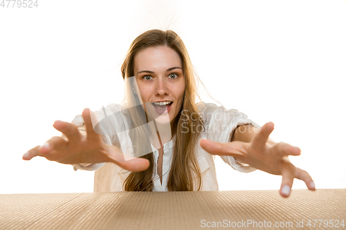 Image of Young woman opening the biggest postal package isolated on white