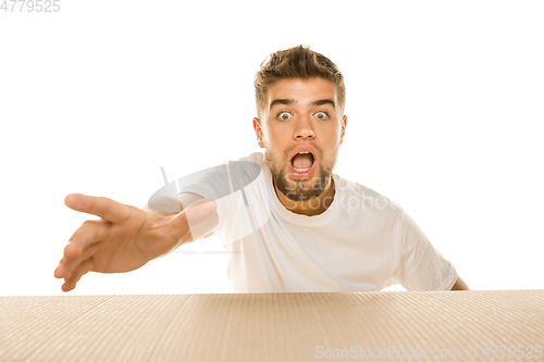 Image of Young man opening the biggest postal package isolated on white