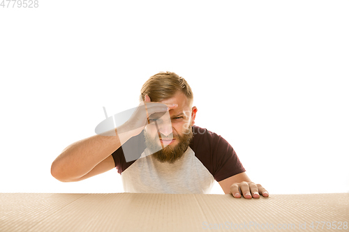 Image of Young man opening the biggest postal package isolated on white