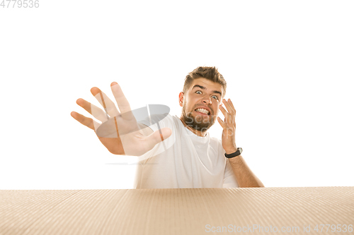 Image of Young man opening the biggest postal package isolated on white