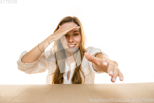 Image of Young woman opening the biggest postal package isolated on white