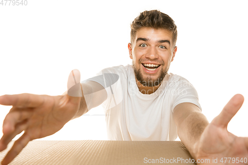 Image of Young man opening the biggest postal package isolated on white